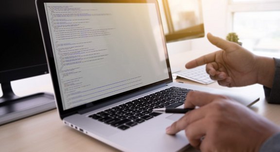 Hände auf einem Laptop, der Programmiercode zeigt, symbolisieren professionelle Website-Optimierung und Wartung