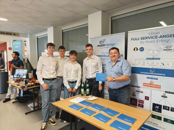 Schülergruppe der HTL Pinkafeld mit einem Vertreter von master design beim Karrieretag 2025 am Unternehmensstand.